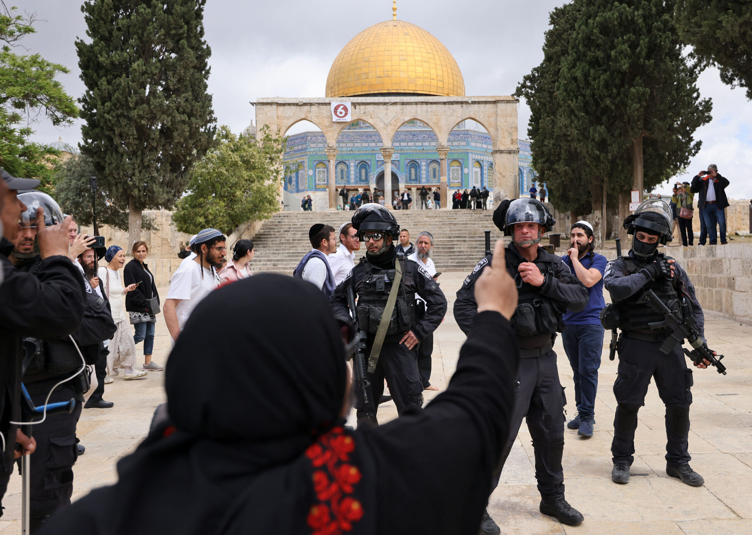 A Palestinian woman gestures as Israeli police accompany a group of Jewish visitors past the Dome of the Rock mosque at the al-Aqsa mosque compound in the Old City of Jerusalem on May 5, 2022. - Clashes erupted between Israelis and Palestinians at Jerusalem's Al-Aqsa mosque compound, after a 10-day cooling of tensions at the holy site, Israeli police said. The Israeli police said they had repelled "dozens of rioters" who had been "throwing stones and other objects" at the security forces. (Photo by AHMAD GHARABLI / AFP) (Photo by AHMAD GHARABLI/AFP via Getty Images)
