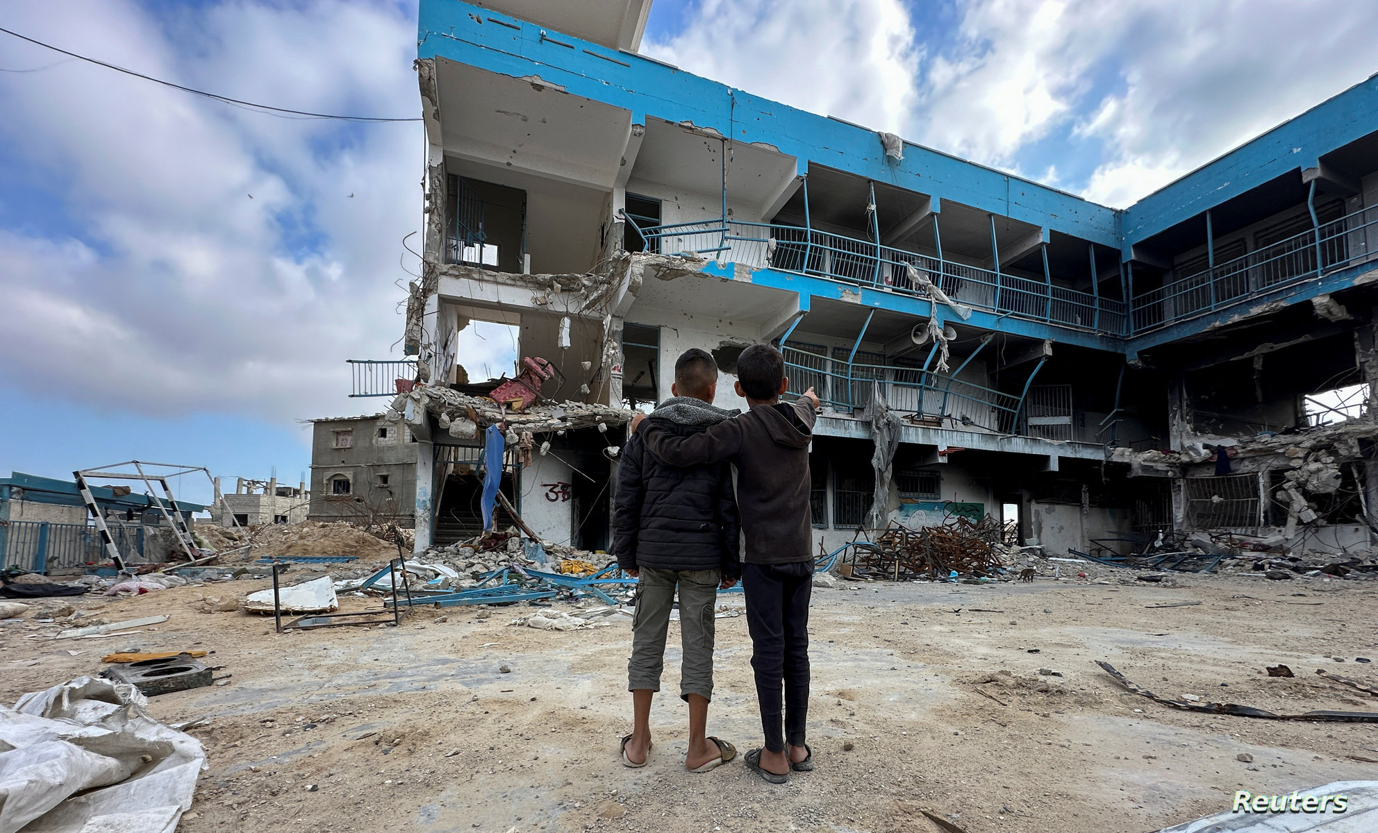 Palestinian school children Abed Al-Qara and Muhammad Al-Fajem view their school which was destroyed during Israel's military offensive, amid the ongoing conflict between Israel and Hamas, in Khan Younis in the southern Gaza Strip, April 14, 2024. REUTERS/Doaa Rouqa